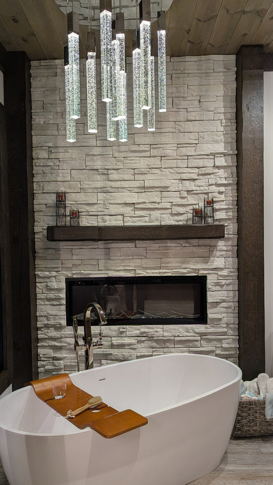 Modern bathroom with freestanding bathtub, timber mantel, decorative timber posts, stone fireplace, and decorative lighting.